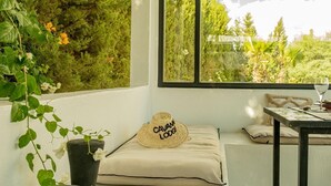 A cozy seating area with a view of a lush garden, a table with a glass, and a hat with "CAVAN LODGE" on it. - Cavanna Lodge (Ounagha)