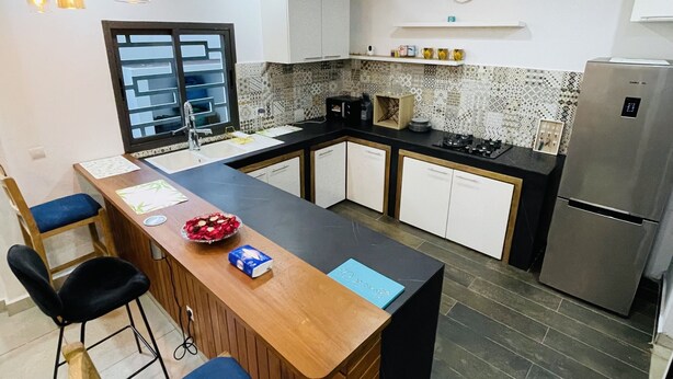 Una cocina moderna con una isla central, taburetes de bar, un refrigerador y un salpicadero con diseño.