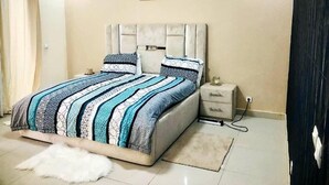 Un dormitorio con una cama grande, una mesita de noche y un tocador.