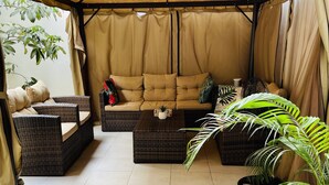 Un espacio de estar al aire libre cubierto con un sofá, dos sillones y una mesa de centro.