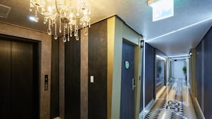 A hotel corridor with a chandelier, elevators, and patterned flooring. - ON & OFF HOTEL (Incheon)