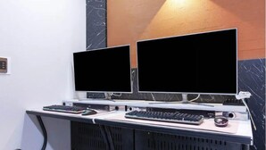 A dual-monitor workstation with a keyboard, mouse, and a small speaker. - ON & OFF HOTEL (Incheon)