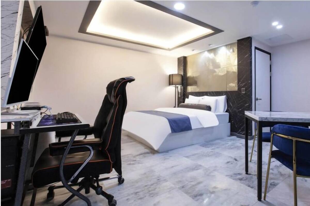 Habitació d'hotel moderna amb llit, escriptori, cadira i taula petita.