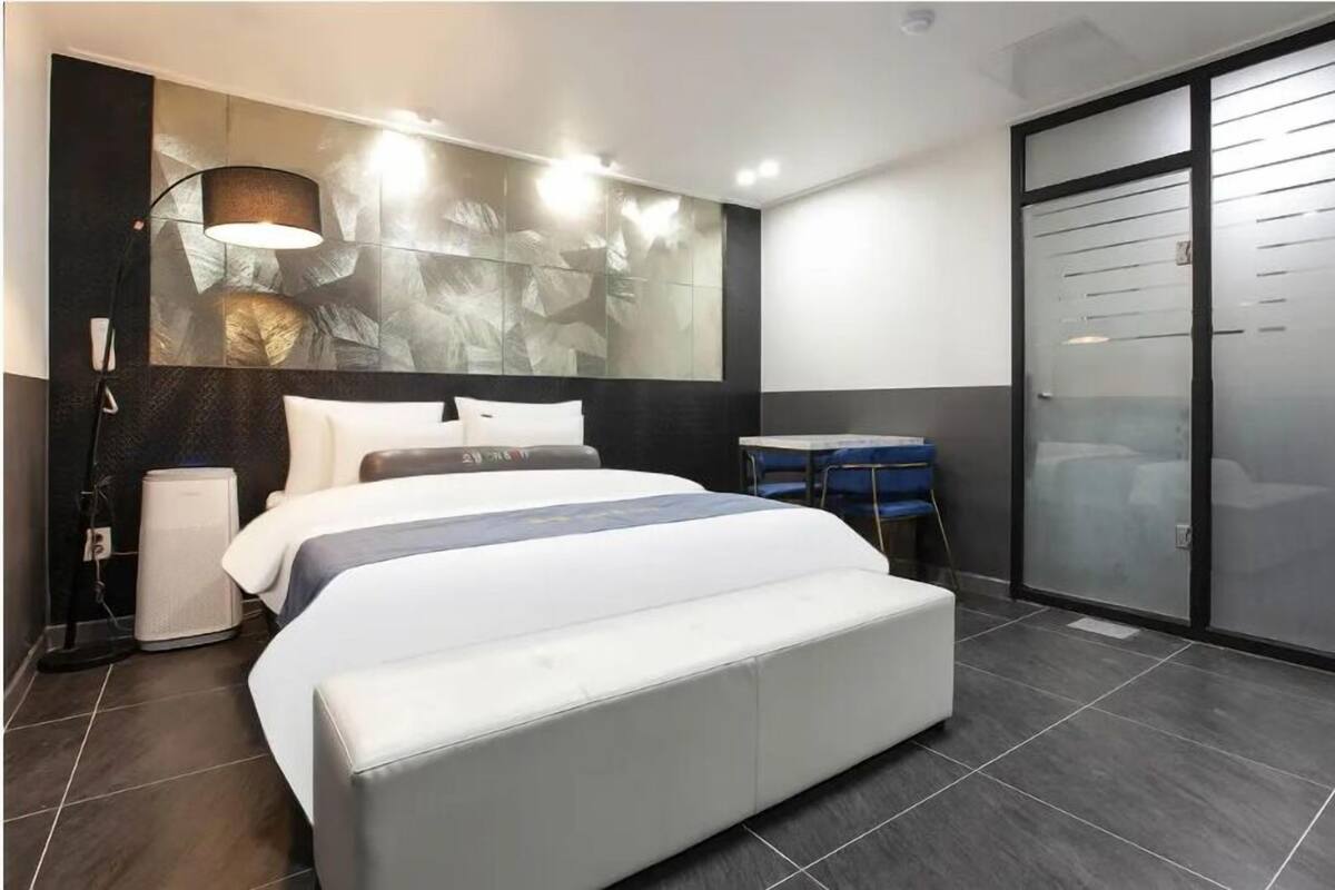 Una habitació d'hotel moderna amb un llit gran, una taula de treball, una cadira i un armari.