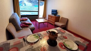 Un salon meublé comprenant un canapé, un fauteuil, une table basse et un meuble pour la télévision.
