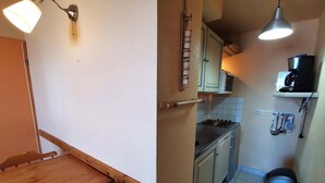 A compact kitchen with a wooden table and chairs, a stove, and a coffee machine. - 2-bedroom apt at the foot of the slopes, balcony and elevator (Les Adrets-Prapoutel)
