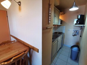 Eine kleine Küche mit Holztisch und -stühlen, einem Herd und einer Kaffeemaschine.