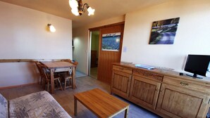 A cozy living room with a wooden sofa, a wooden coffee table, a dining table with chairs, a wooden cabinet, and a television. - 2-bedroom apt at the foot of the slopes, balcony and elevator (Les Adrets-Prapoutel)