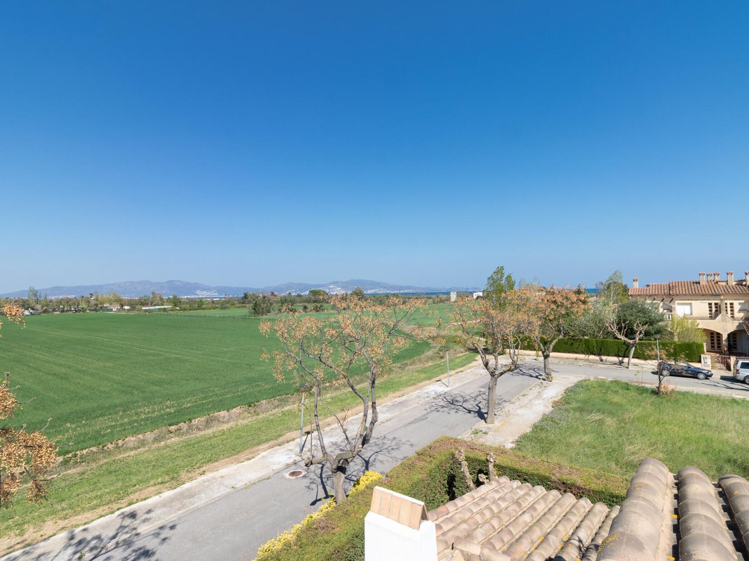 Ein Wohngebiet mit freiem Blick auf ein grünes Feld, eine Straße und ein Gebäude mit einem Ziegeldach.