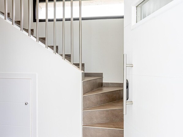 A staircase with metal railings and a door on the left.