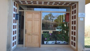 A building entrance with a wooden door, a window with a view of a car and a house, and a sign reading "TORRE CANIGO 22". - Apt 6 People, Parking, Air Con, Stunning View (Sant Pere Pescador)