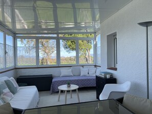 A sunroom with a sofa, a small table, and a chair. - Spacious Costa Brava Home: BBQ, WiFi, Parking, Near Beach, Sleeps 7 (Sant Pere Pescador)