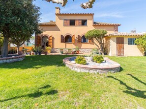 A two-story house with a courtyard, stone walls, and potted plants.
