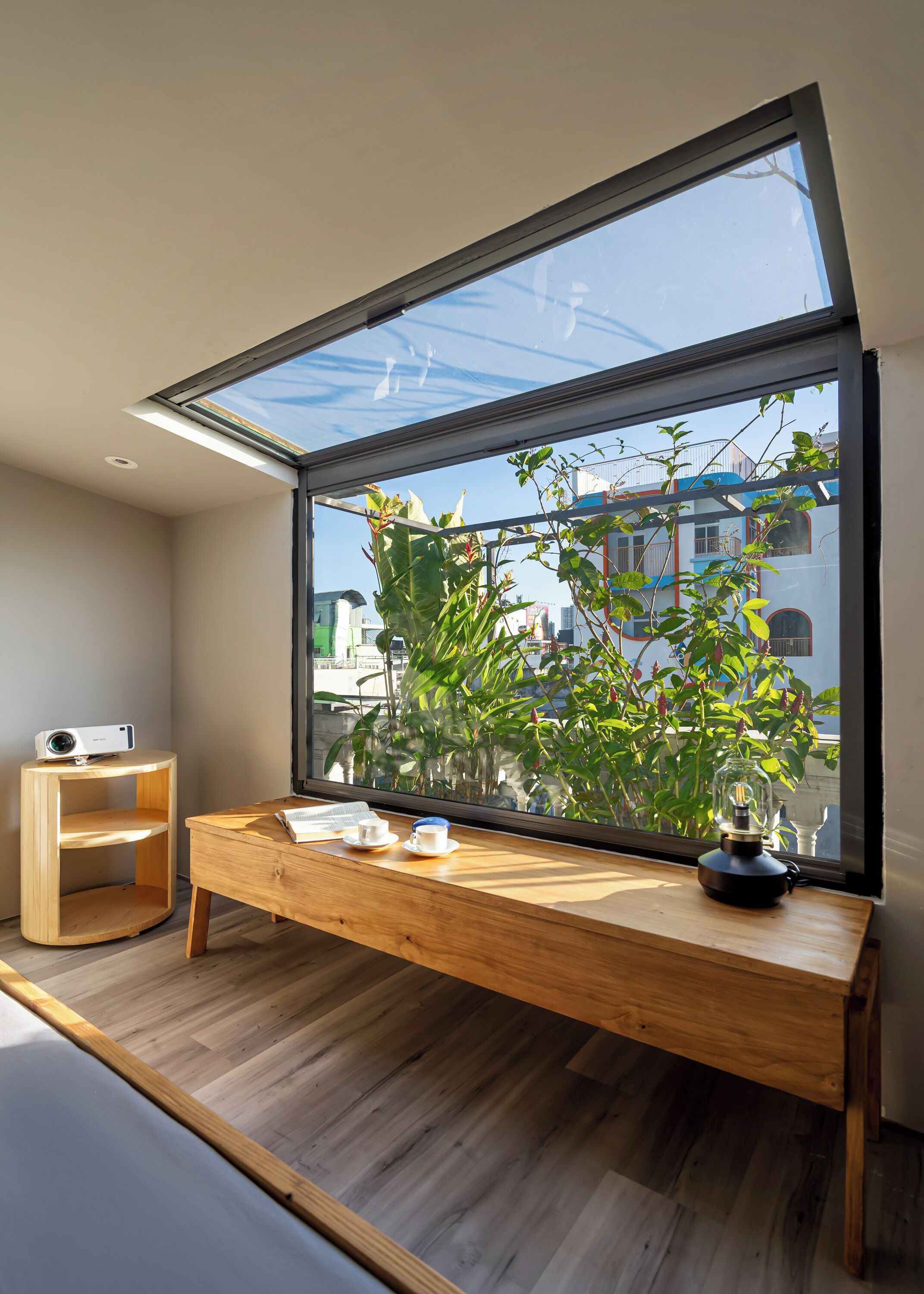 A modern room with a large skylight, a wooden desk with a lamp, and a projector.