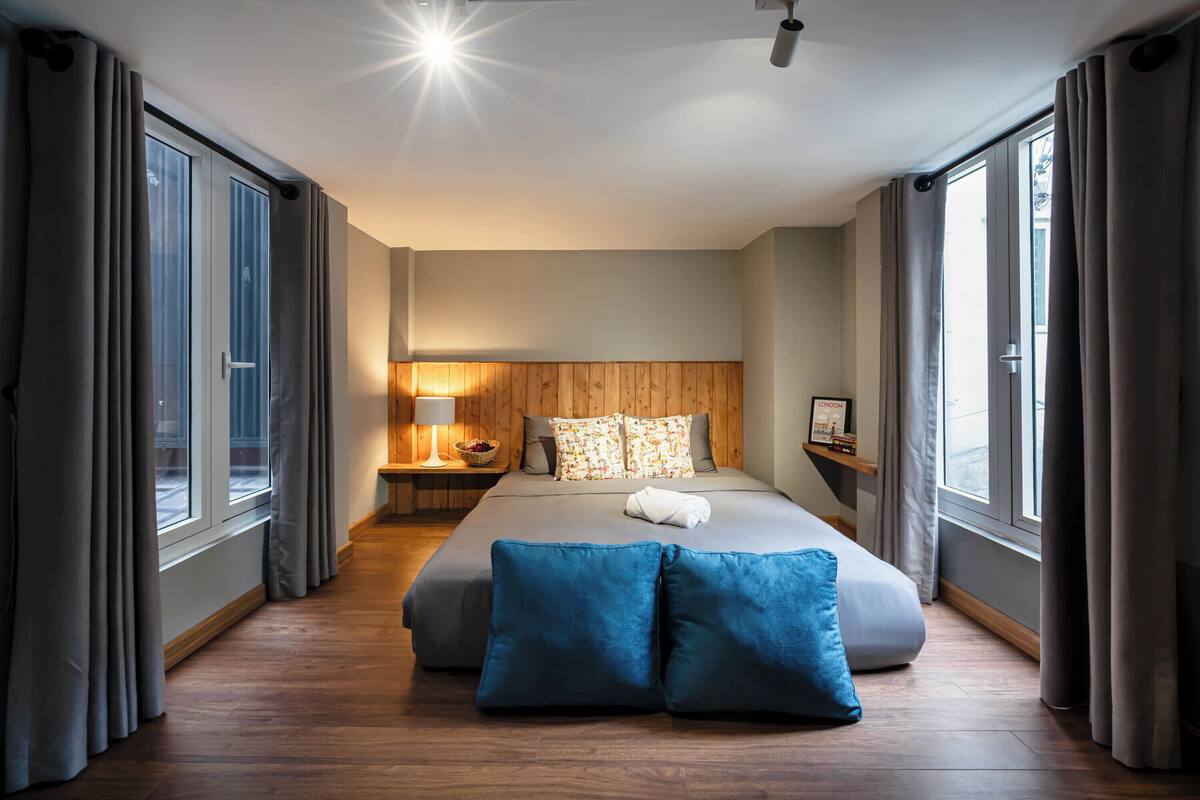 Een moderne hotelkamer met een groot bed, een houten hoofdeinde en uitzicht door het raam.