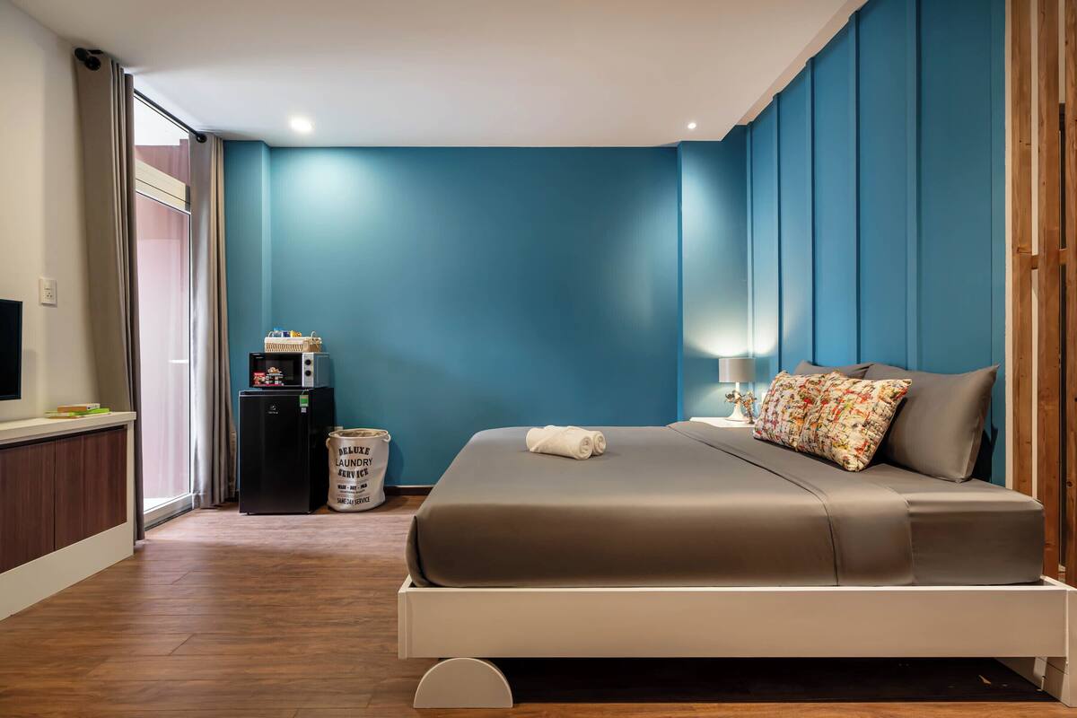 Een moderne slaapkamer met een groot bed, een kleine koelkast en een televisie aan de linker muur.