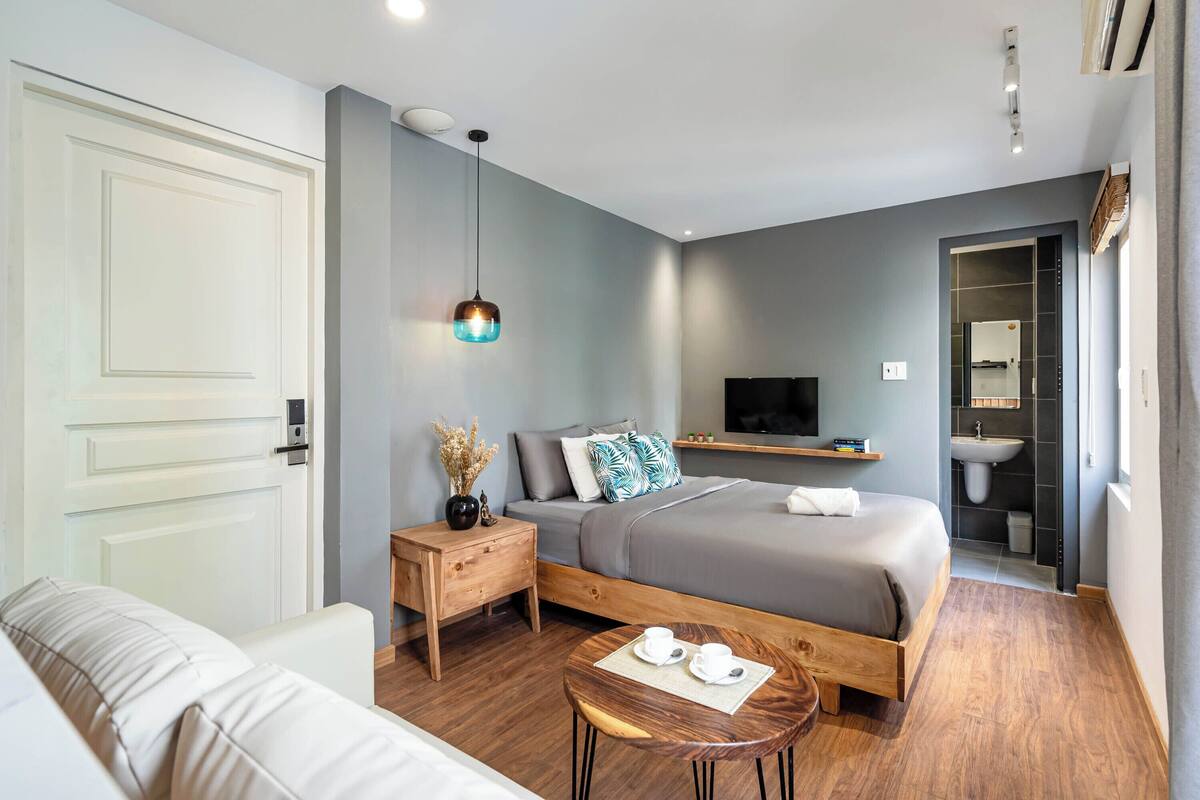 Een moderne hotelkamer met een bed, nachtkastje, televisie en een zichtbare badkamer door een geopende deur.