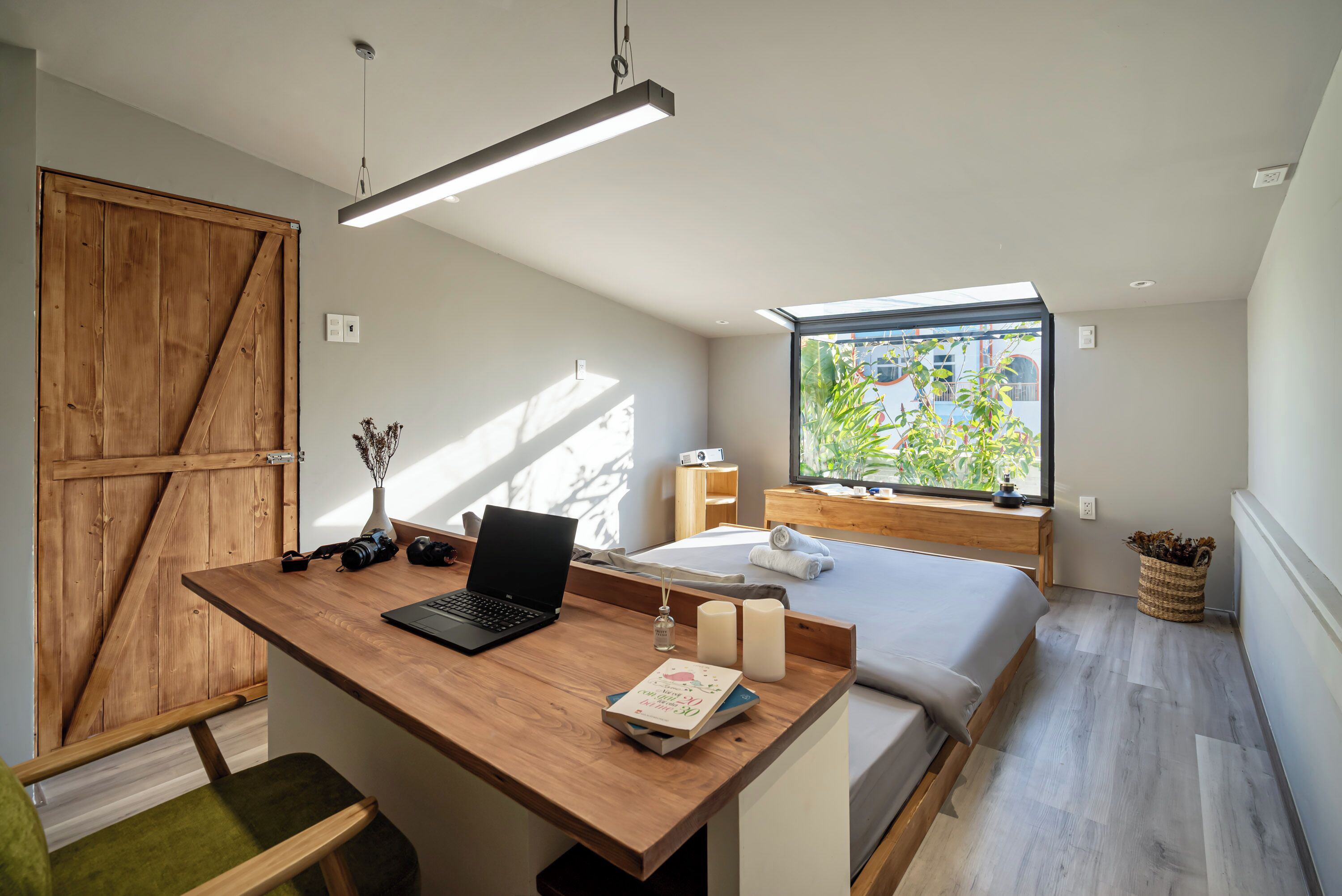 Un dormitorio moderno con un escritorio de madera, una cama y un amplio ventanal.