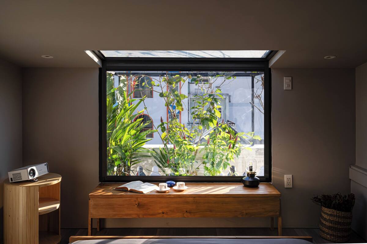 Een kamer met dakraam, een houten bureau met een boek, twee bekers en een projector.