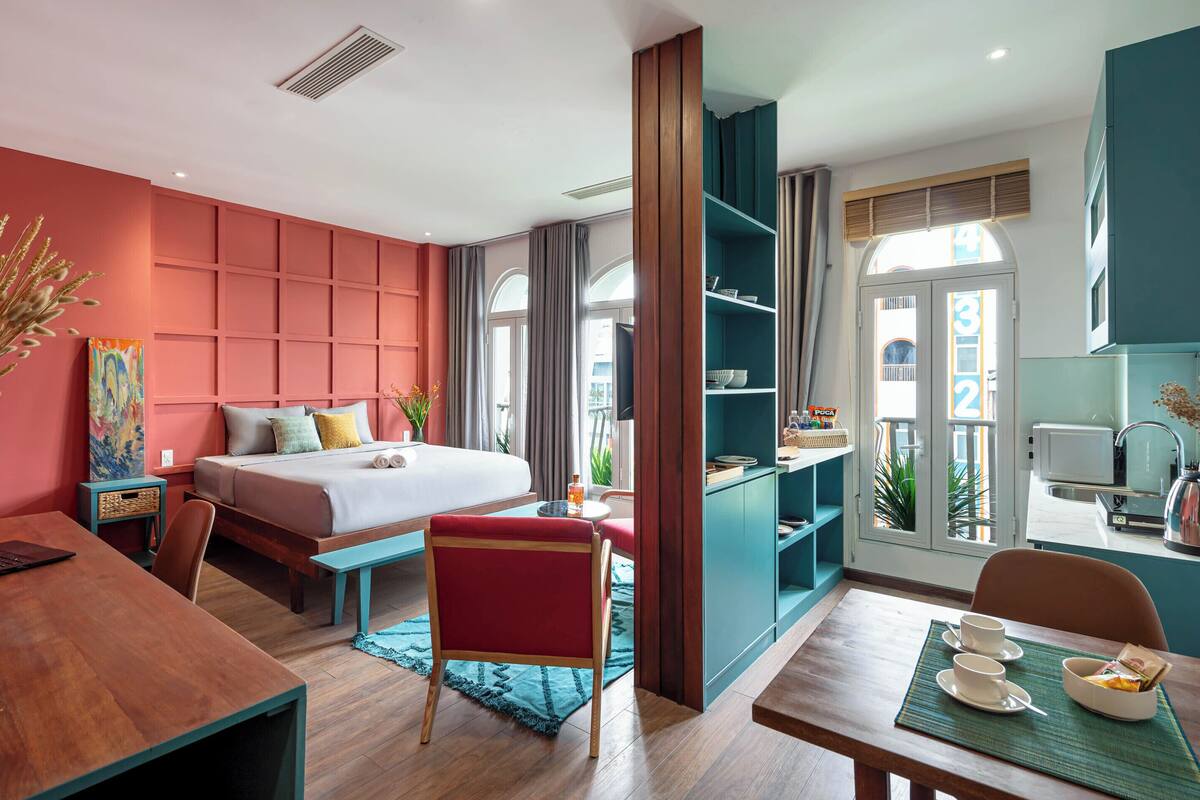 Een moderne hotelkamer met een bed, bureau, stoel en kitchenette.