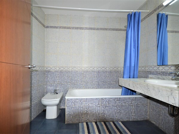 A bathroom with a toilet, bidet, and bathtub.