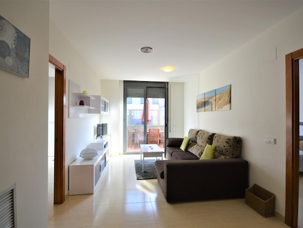 Una sala moderna con un sofá, un televisor y una pequeña cocina.