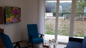 Una sala de estar con una silla azul, un sofá y una pequeña mesa con un libro y una tetera.