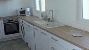 Una cocina moderna equipada con microondas, cafetera, lavaplatos y lavadora.