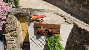A courtyard with a stone wall, potted plants, and a wooden bench. - House in granite stone with a century old in center Portugal. Open Space. (Tinalhas)