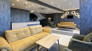 A modern lobby with a sofa, armchairs, a coffee table, and a staircase. - ALARGA PREMIER (Trabzon)