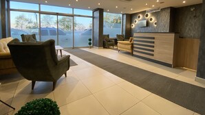 A modern reception area with a reception desk, seating, and large windows. - ALARGA PREMIER (Trabzon)
