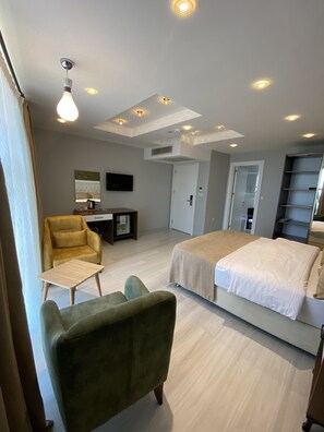 A modern hotel room with a bed, a desk, a chair, and a TV.