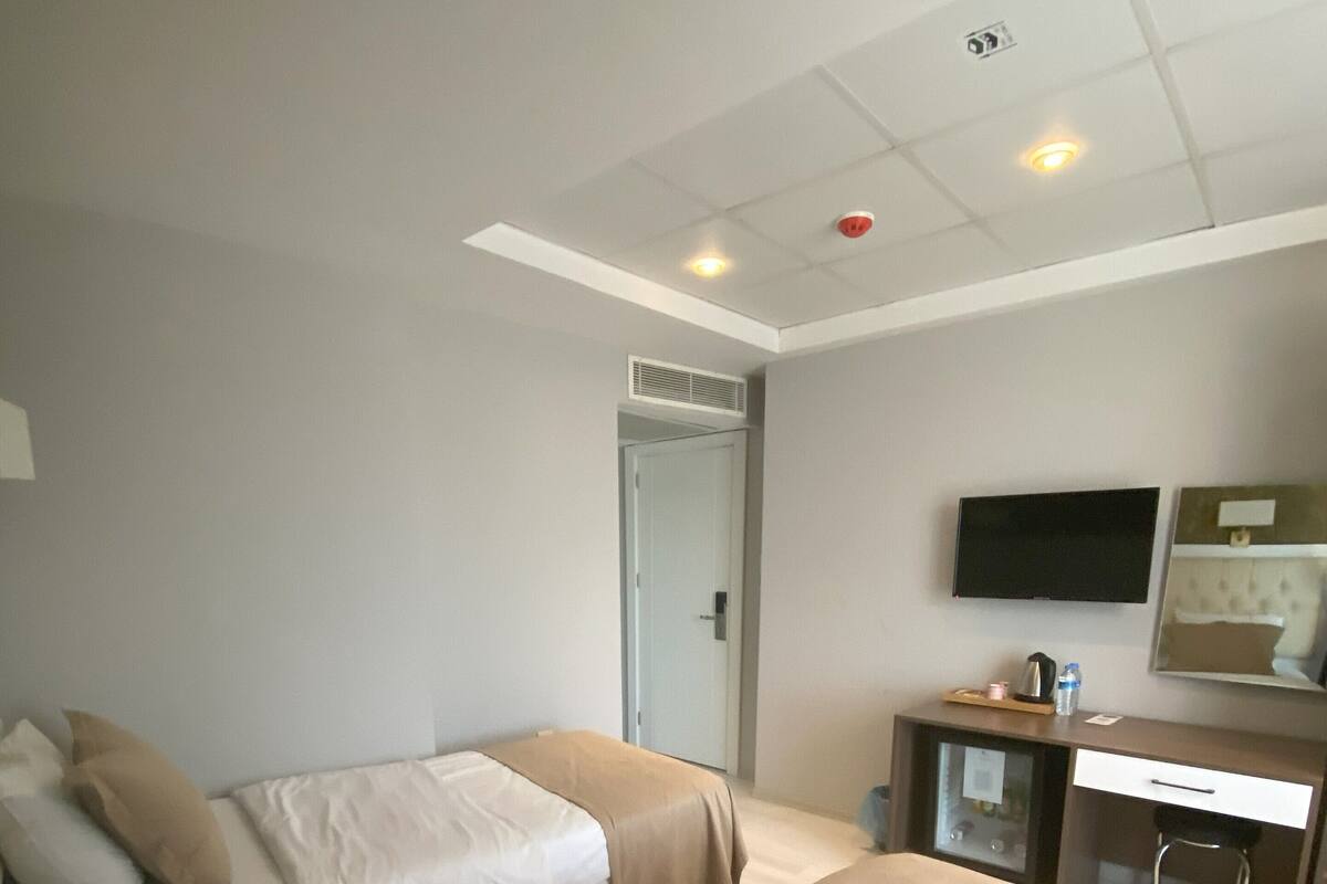 A hotel room with two beds, a desk, a chair, a television, and a door.