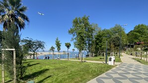 A park with a paved walkway, benches, and trees. - ALARGA PREMIER (Trabzon)