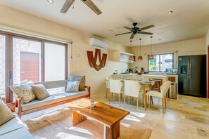 Enjoy a spacious living space with a dining area, large window, ceiling fan, and air conditioning.