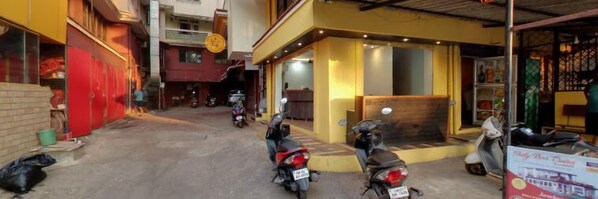 A narrow street with parked scooters and a building with a yellow facade. - Marine Castle (Panaji)
