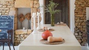 A rustic interior with a stone wall, a wooden door, a chalkboard menu, and a table with fruits and a vase. - Maison Lou Piade (Sarlat-la-Canéda)