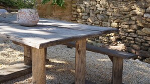 A rustic outdoor seating area with a stone wall backdrop, a wooden bench, and a potted plant. - Maison Lou Piade (Sarlat-la-Canéda)