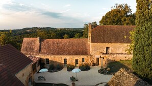 A stone building with a courtyard, featuring a gravel path and potted plants. - Maison Lou Piade (Sarlat-la-Canéda)
