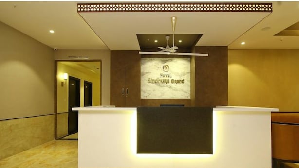 A reception desk with a modern design, a ceiling fan, and a sign above it. - Sindhura Grand (Hyderabad)