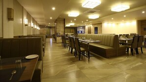 A restaurant with booths and tables, a long counter, and a staircase leading to an upper level. - Sindhura Grand (Hyderabad)