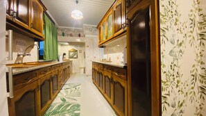 Eine Küche mit Holzschränken, einem grün gemusterten Boden und einem Kühlschrank.