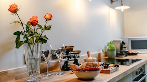 Una encimera de cocina con un jarrón de rosas, un tazón de bayas y varios utensilios de cocina.