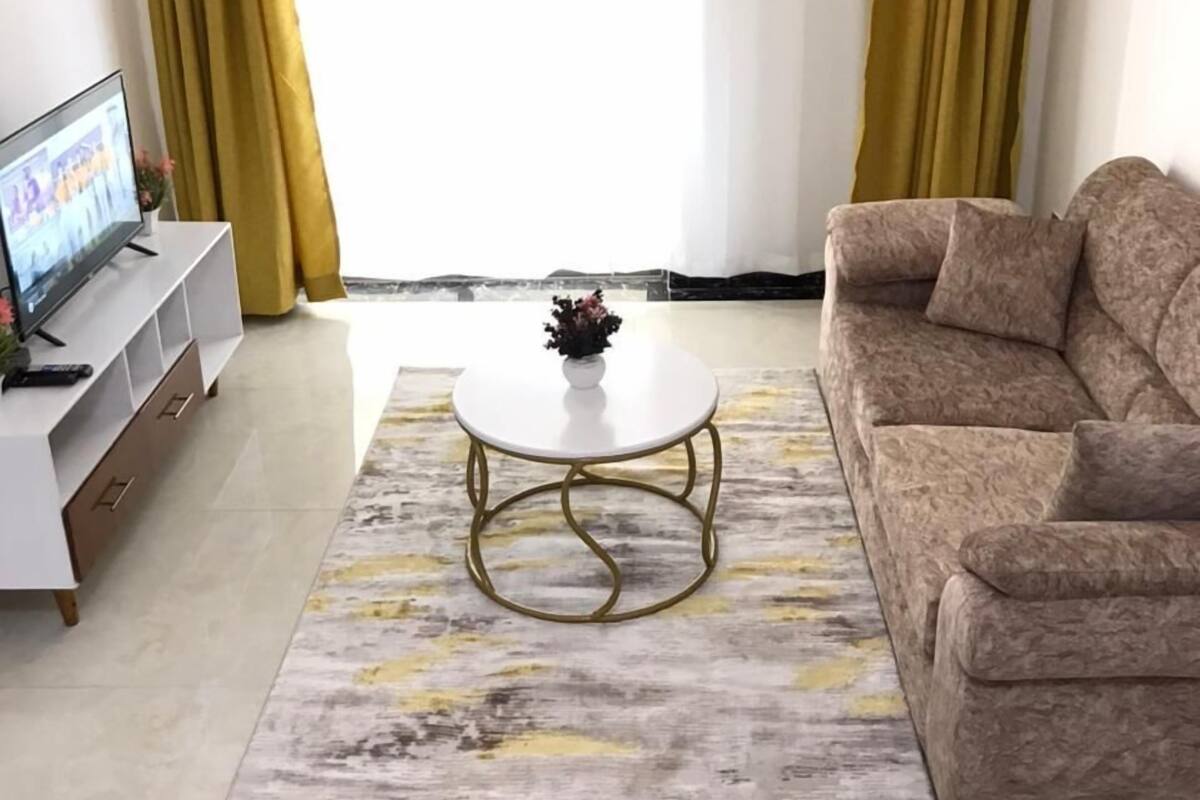 A living room with a sofa, a coffee table, a TV, and curtains.