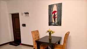 Ein Essbereich mit Tisch und vier Stühlen, einer Vase mit Blumen und einem Bild an der Wand.