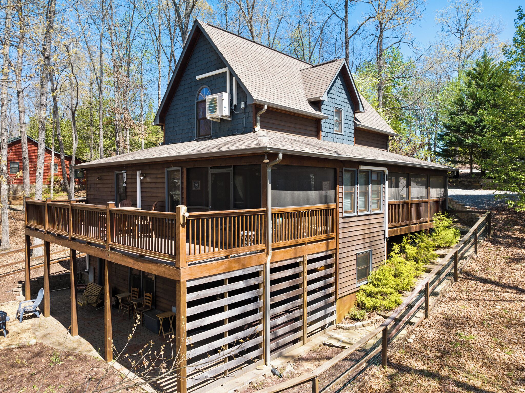 Une cabane en bois à deux étages, dotée d’un balcon, d’une véranda couverte et d’une petite terrasse.