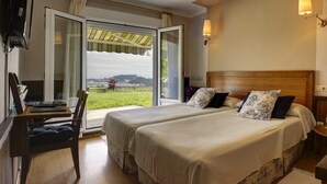 A hotel room with two beds, a desk, and a chair. - Hotel Mirador del Sella (Ribadesella)