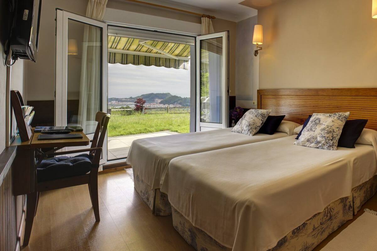 Een hotelkamer met twee bedden, een bureau en een stoel.
