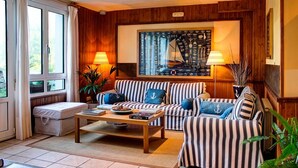 A cozy living room with striped sofas, a coffee table, and a large nautical-themed artwork on the wall. - Hotel Mirador del Sella (Ribadesella)