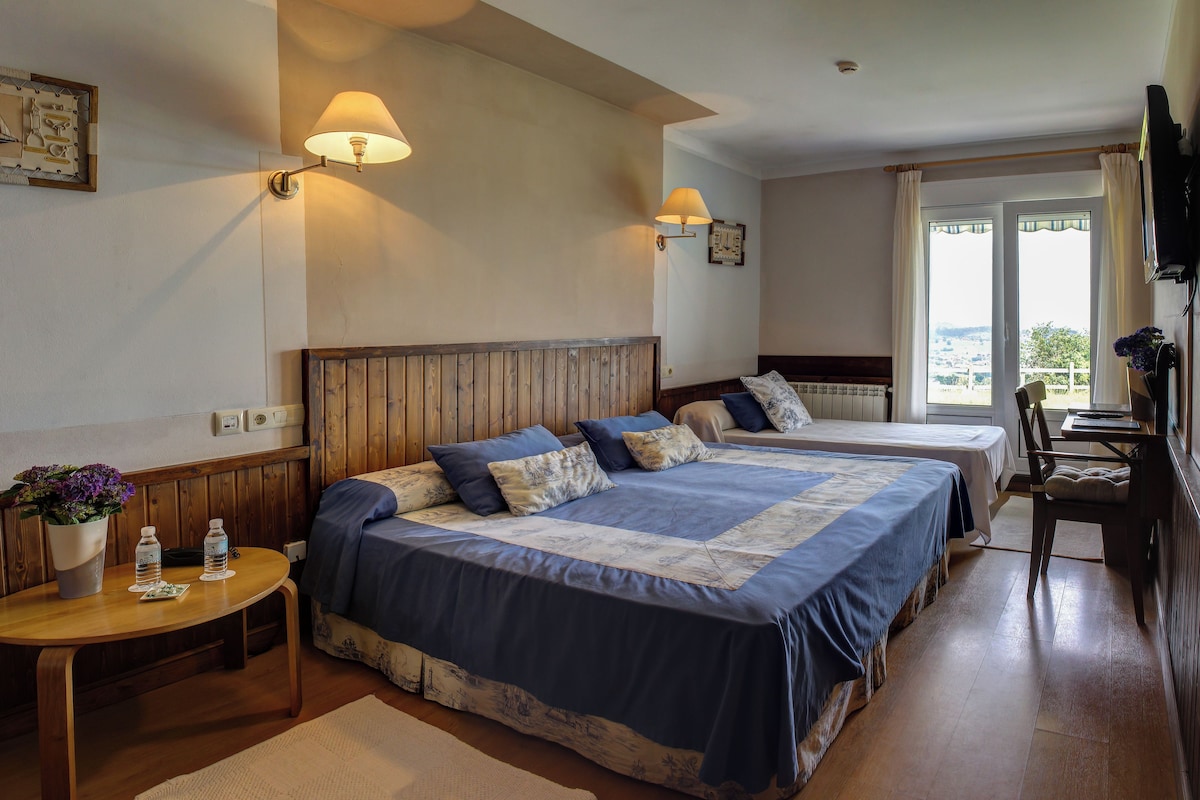 Une chambre d’hôtel avec deux lits, une tête de lit en bois, des lampes de chevet, une petite table avec une plante et une vue par la fenêtre.
